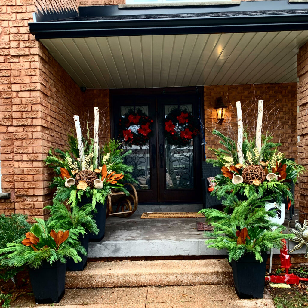 Covered porch with candles and red winter planters at the door