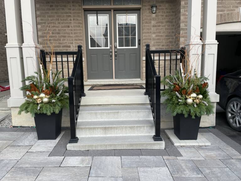 Matching winter planters at the foot of stairs to a grey double door