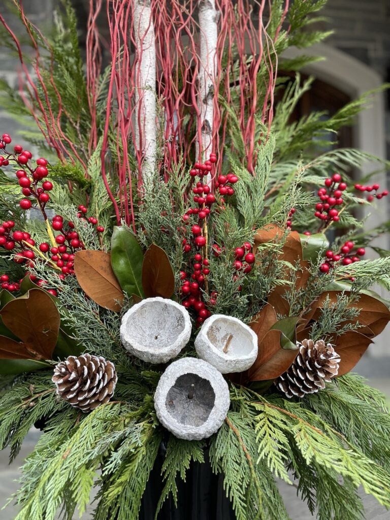 Classic red winter planter with magnolia leaves, red berries, pine cones and white birch rounds