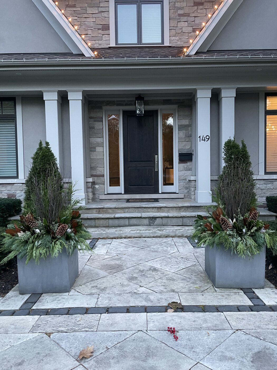 Cedar topiaries and evergreen planters flanking a front entrance in winter